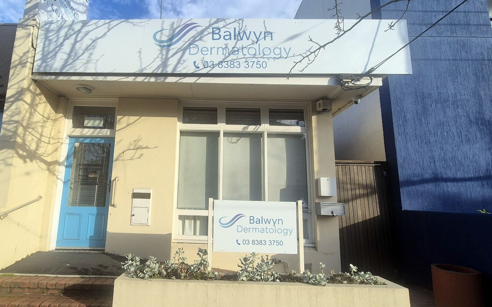 Balwyn Dermatology's shopfront on High Street, Kew East, with the clinic sign above and a blue front door